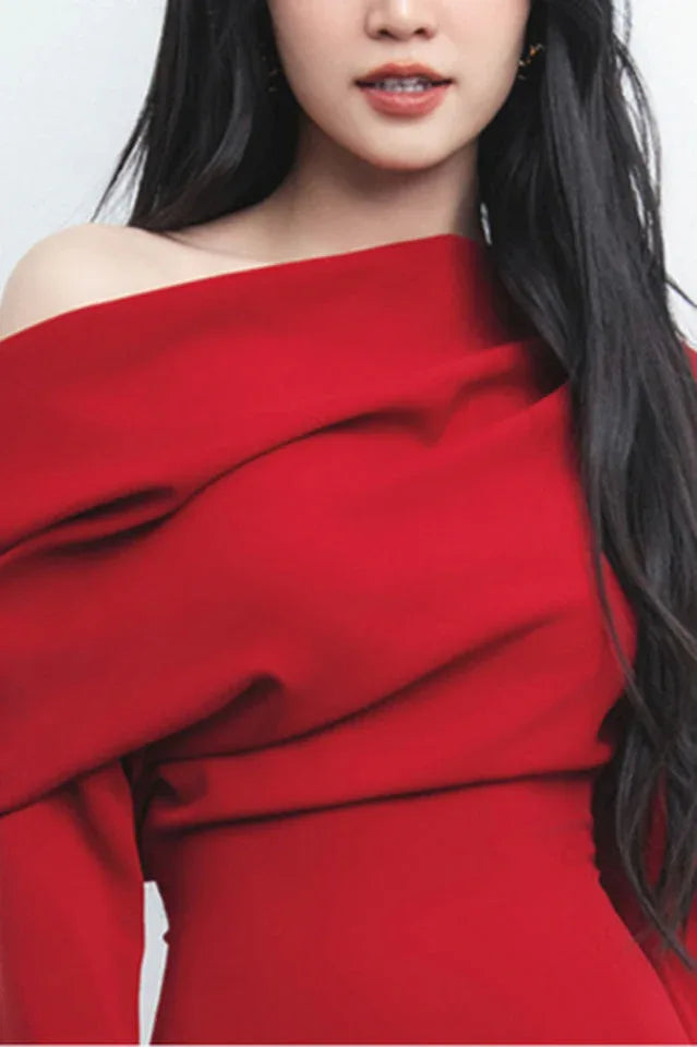 Close-up of the draped neckline and off-the-shoulder design of a red dress.
