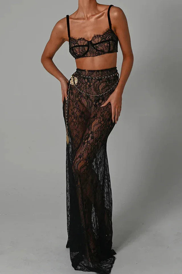 Woman wearing a black lace bralette and a sheer black lace maxi skirt with a gold chain belt. Main image