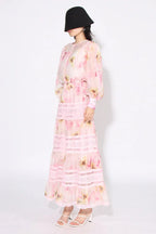 Woman wearing a pink floral print maxi dress from the side