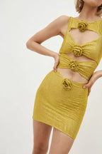 Close-up of a woman's torso wearing a gold metallic knit mini dress with cut-out details and floral appliqués