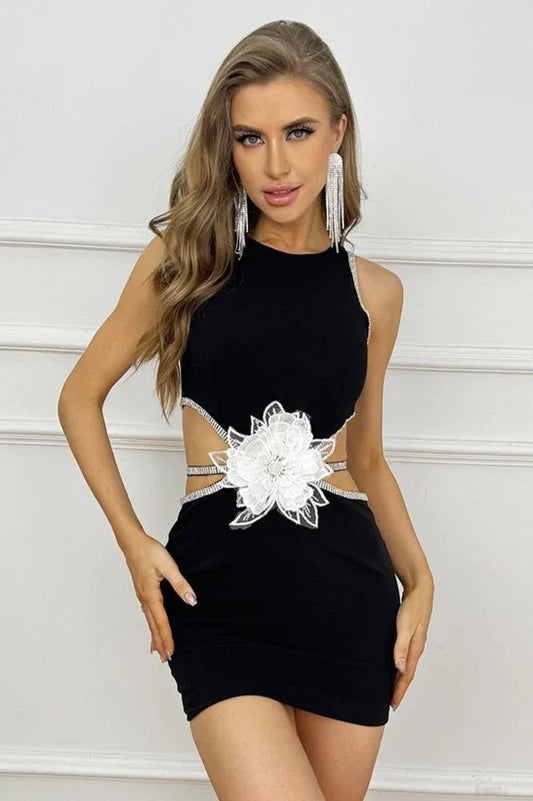 Woman wearing a black sleeveless dress with side cutouts and a white floral applique