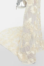 Close-up of the train of an ivory gown with intricate gold floral embroidery.