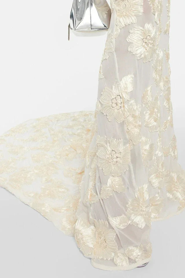 Close-up of the train of an ivory gown with intricate gold floral embroidery.