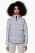 Woman wearing a light grey puffer vest over a grey sweatshirt and grey leggings