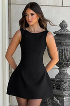 Woman wearing a black sleeveless boat neck mini dress standing outdoors.