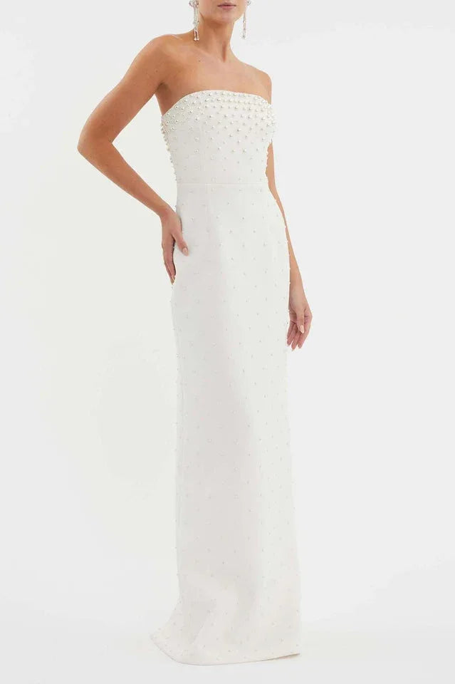 Woman wearing a white strapless pearl-embellished column gown, posing with hands on hips