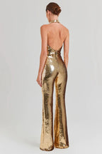 Woman wearing a gold sequined halter neck jumpsuit with wide leg pants, back view.