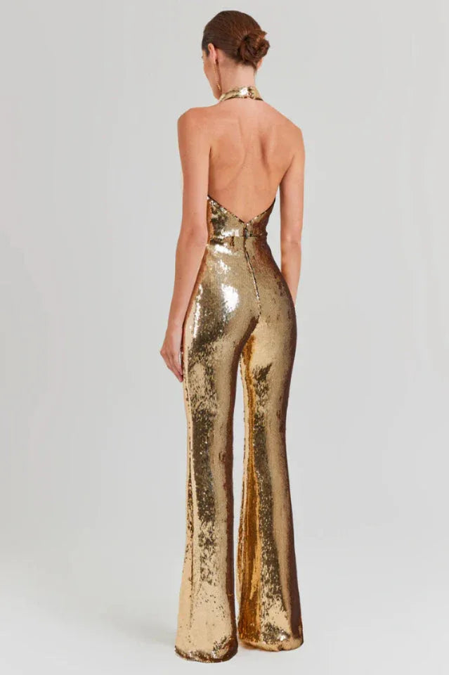 Woman wearing a gold sequined halter neck jumpsuit with wide leg pants, back view.