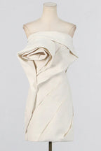 Mannequin displaying an off-white strapless dress with a large rose detail on the bodice and pleated skirt.