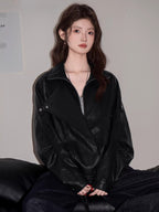 Woman wearing a black faux leather jacket with lapel collar and asymmetrical zipper, paired with a grey crop top and dark wash jeans.