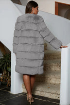 Rear view of a woman wearing a gray faux fur coat and heels on a staircase.