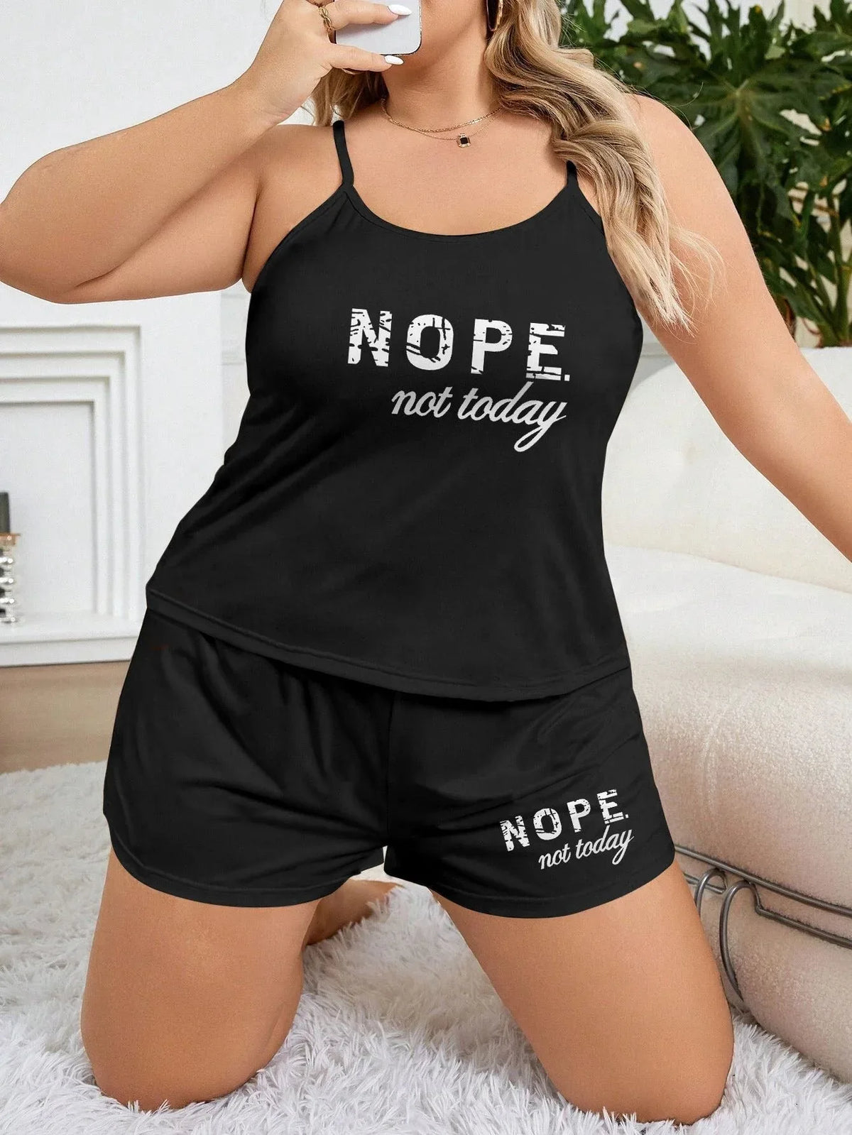 Woman in a black pajama set with 'NOPE. not today.' graphic print, posing on a rug.
