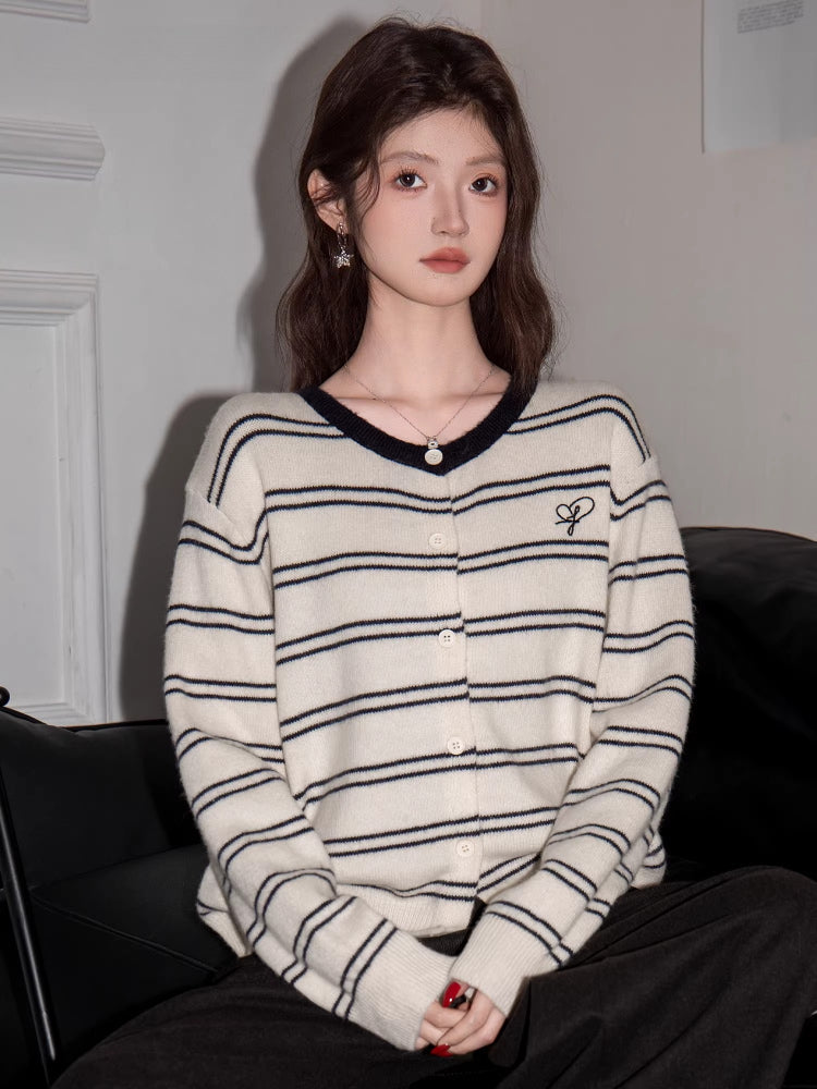 Close-up of a woman wearing a cream and black striped button-up knit cardigan.