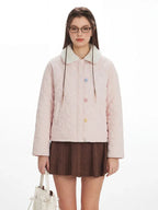 Close-up of a model wearing a pink quilted jacket with a faux fur collar and colorful star buttons.