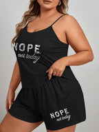 Woman wearing a black pajama set with 'NOPE. not today.' graphic print on the camisole and shorts.