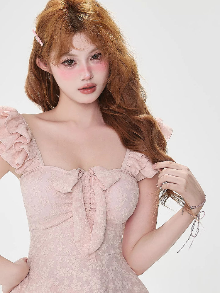 Close-up of the bodice of a pink tiered dress with a bow accent