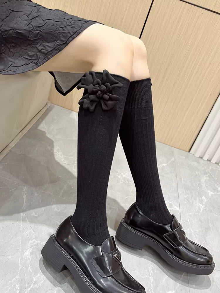 Close-up of black knee-high socks featuring a 3D flower detail on the side.