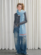 Model standing with hands at sides, wearing a scarf and jeans.