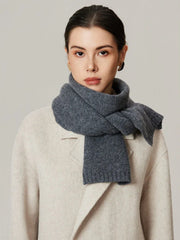 Close-up of a woman wearing a grey knit scarf and a cream coat.
