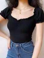 Front view of a black ribbed knit top with a ruched sweetheart neckline and ruffled edges.