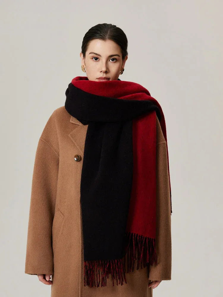 Woman wearing a camel coat and a red and black color-blocked scarf with fringe