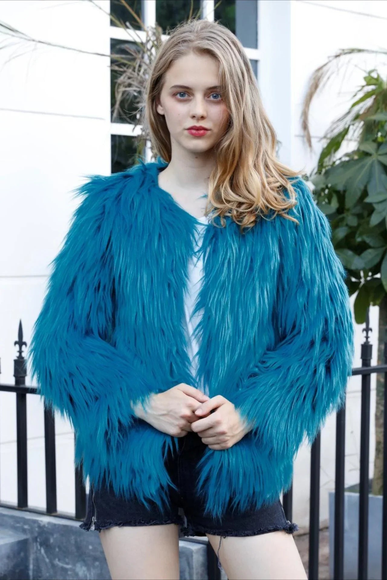Woman wearing a teal faux fur jacket and black shorts Main image