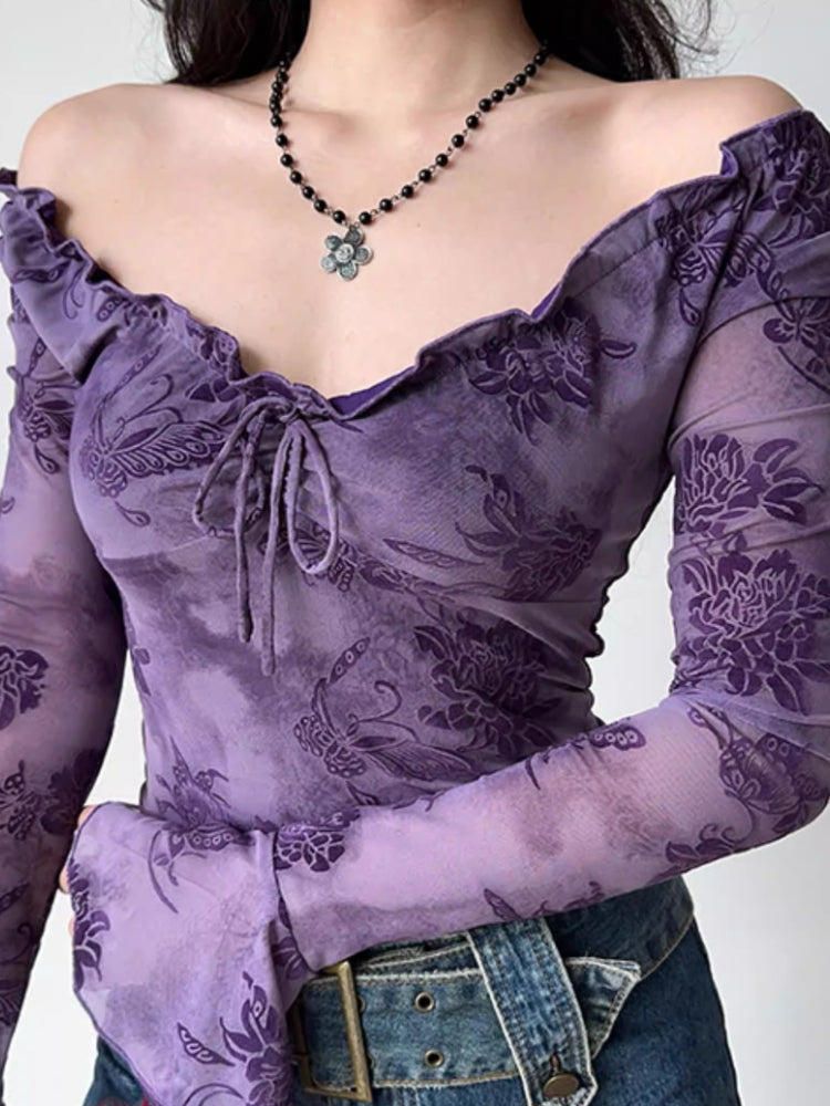 Detail shot of the neckline and sleeves of a purple sheer mesh top with a floral print.