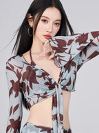 Close-up of the tie-front detail on a light blue and brown floral print sheer mesh top.