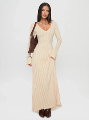 Full-length shot of a woman in a cream ribbed knit maxi dress with a v-neckline and long sleeves.