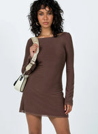 Woman wearing a long sleeve brown mini dress with a boat neckline and a white crossbody bag, front view.