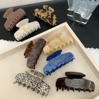 A collection of assorted hair claw clips in various colors and patterns, including tortoiseshell, leopard print, and solid colors.
