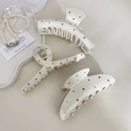 Three cream-colored claw clips with colorful gemstones and a pearl necklace