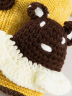 Close-up of the bear applique on a yellow knitted dog sweater.
