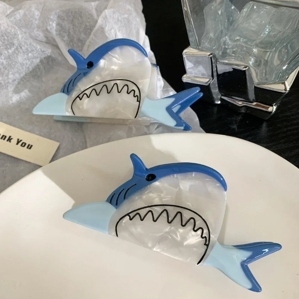 Two blue and white shark hair clips on a white plate