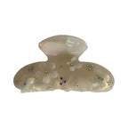 Opaque white claw clip with iridescent sheen, adorned with white floral appliques, small rhinestones, and gold beads.