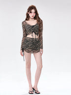 Full body shot of a woman in a sheer striped two-piece set, featuring a crop top and mini skirt.