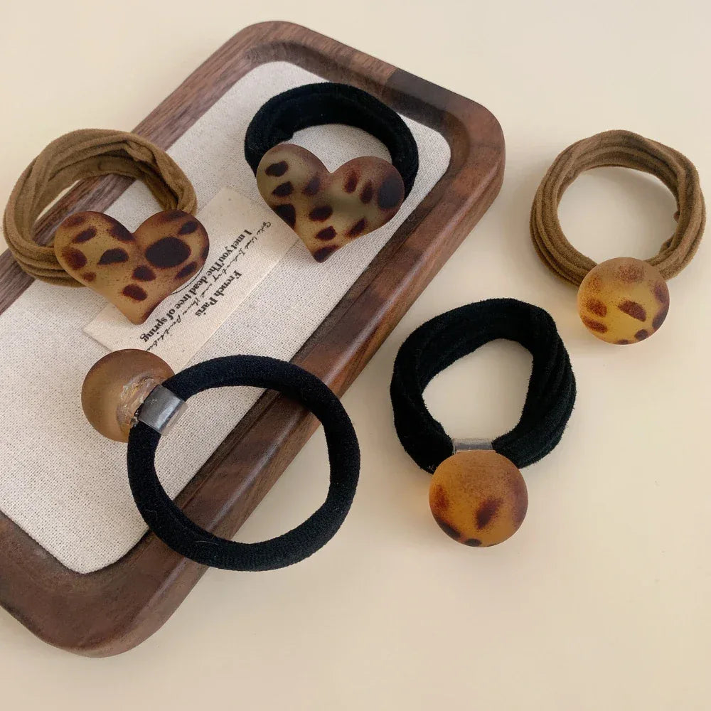 Close-up of leopard print hair ties, including round and heart shapes, arranged on a tray.