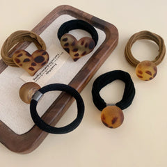 Close-up of leopard print hair ties, including round and heart shapes, arranged on a tray.