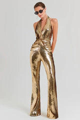 Woman wearing a gold sequined halter neck jumpsuit with wide leg pants and sunglasses, front view.