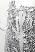 Close-up of the white ribbon lacing through silver eyelets on the side of the sequined shorts.