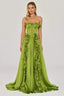 Woman in a green strapless satin gown with ruffled detailing and a high slit, front view.