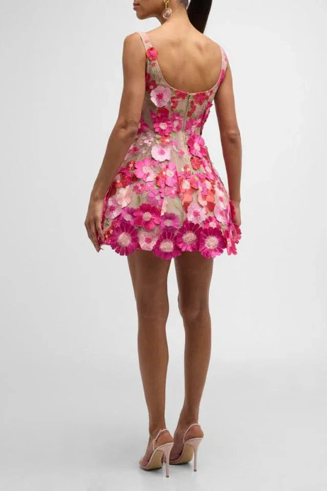 Rear view of a woman in a sleeveless floral mini dress with a scooped back and a flared hemline decorated with numerous flower appliqués.