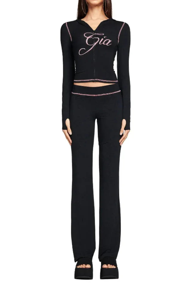 Front view of a black long-sleeve zip-up top with pink 'Gia' embroidery and matching flared pants.