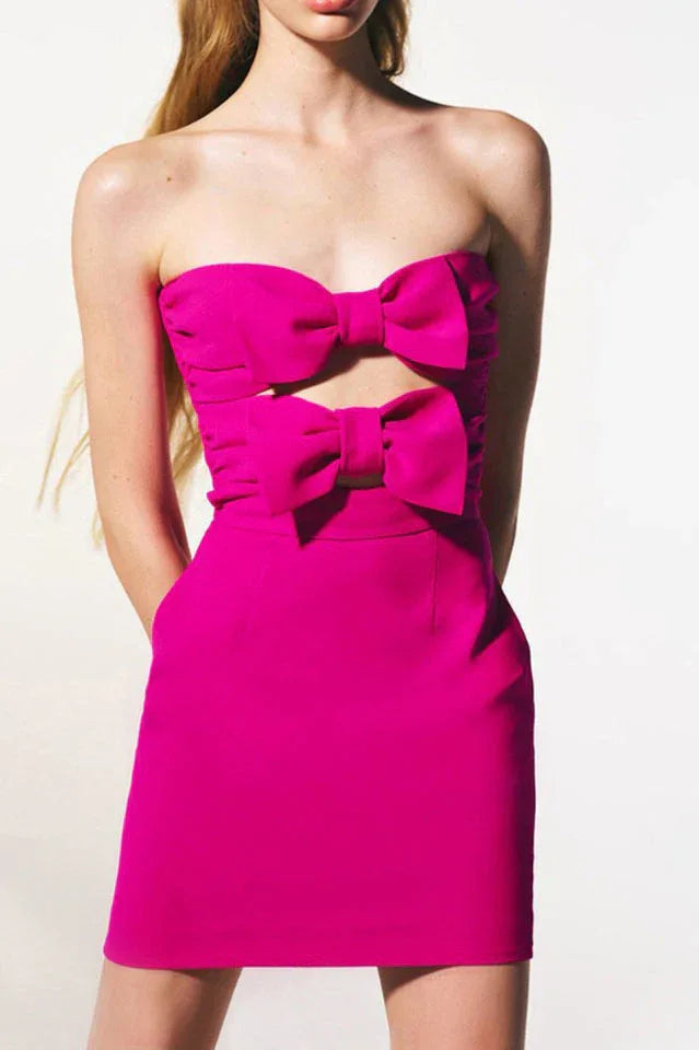 Close-up of a pink strapless mini dress featuring prominent bow embellishments on the bust and a cut-out.