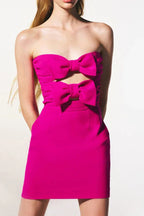 Close-up of a pink strapless mini dress featuring prominent bow embellishments on the bust and a cut-out.