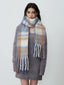 Woman wearing a grey knit dress and a plaid scarf