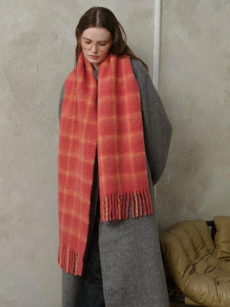 woman standing wearing a grey coat and a red plaid scarf