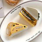 acrylic slice of pizza hair clip and a sandwich hair clip on a white plate with text that says 'Mon cher Paris'