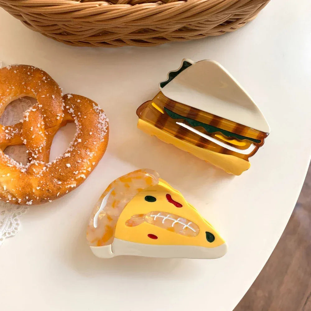 acrylic slice of pizza hair clip and sandwich hair clip next to a pretzel on a white table