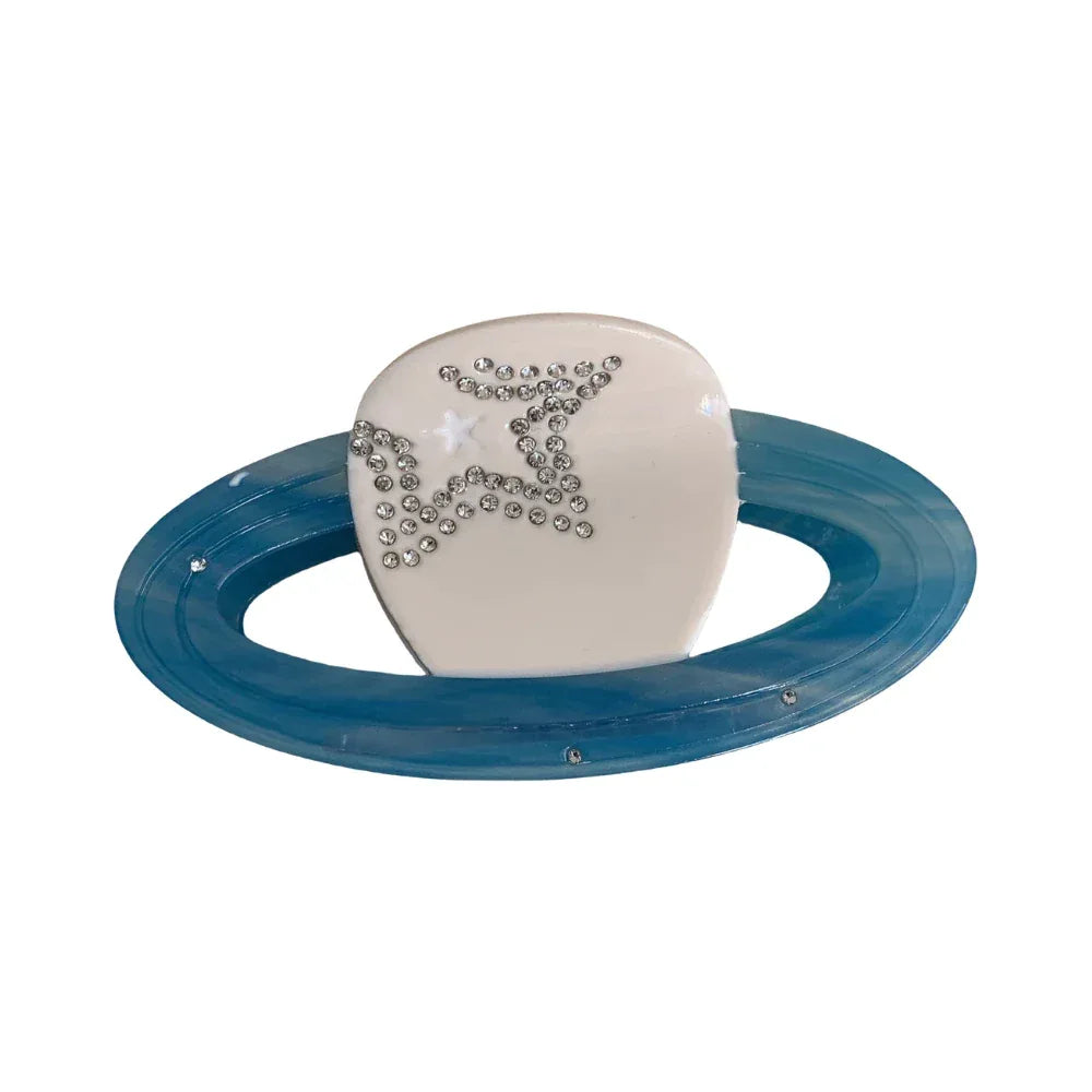 A white planet-shaped hair clip with a blue ring and star embellishments. Main image